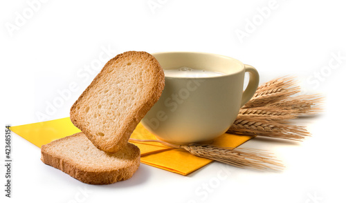 Breakfast set with cup of milk, rusks and ears of wheat, and yellow towel
