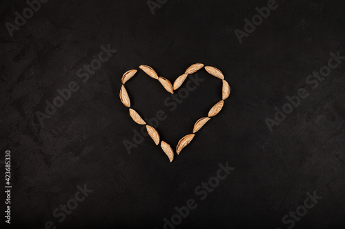 Dried Uzbek wild almonds laid out in shape of heart on dark background
