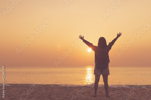 Copy space of woman rise hand up on sunset sky at beach and island background.