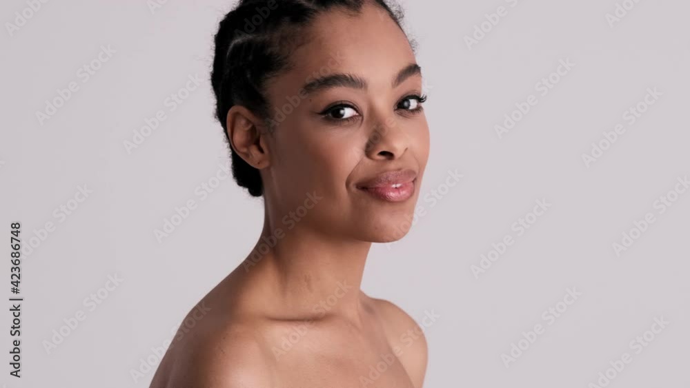 A positive young half-naked woman is whispering something standing isolated over gray background in studio A positive young half-naked woman is whispering something standing isolated over gray background in studio