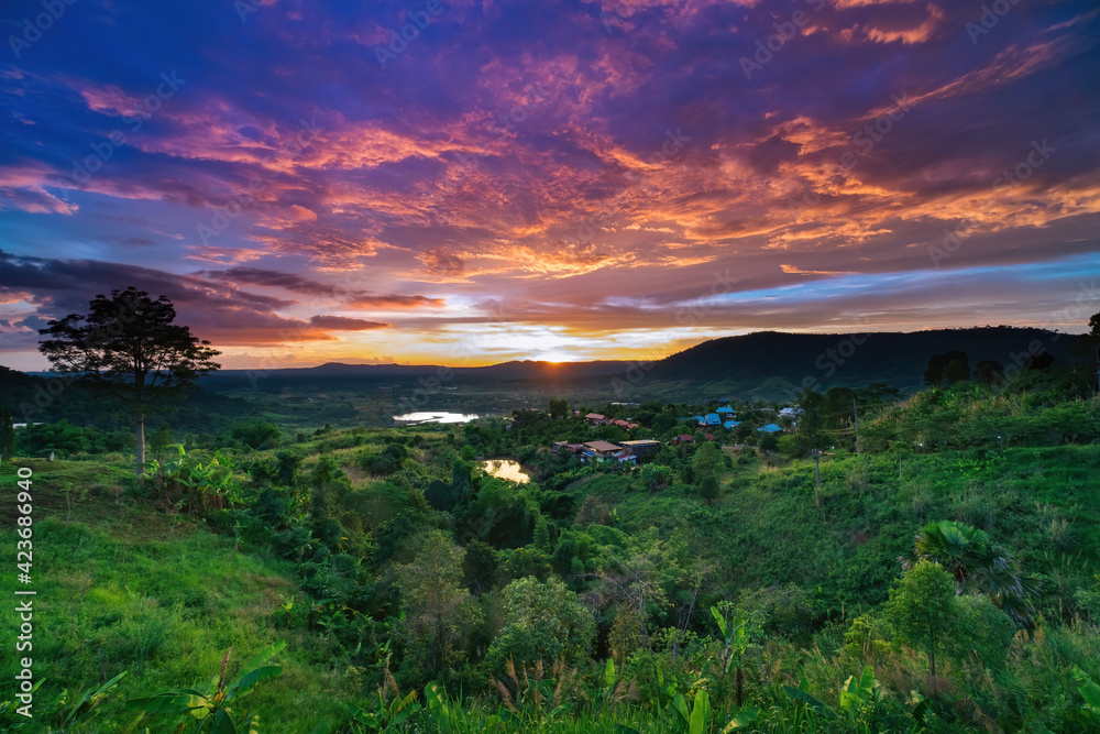 photo of colorful twilight sunset sky at mountian's hills with green field in forground