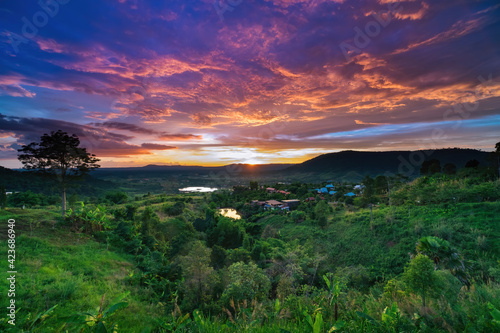 photo of colorful twilight sunset sky at mountian's hills with green field in forground