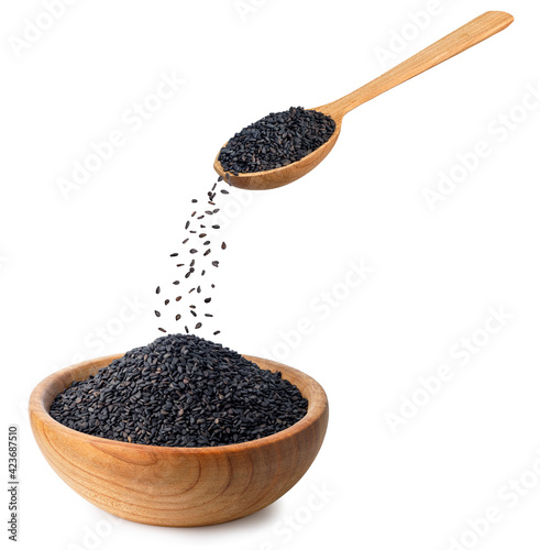 black sesame seeds falling in wooden bowl isolated
