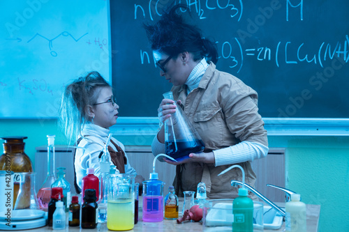 Teacher and little girl during chemistry lesson mixing chemicals in a laboratory