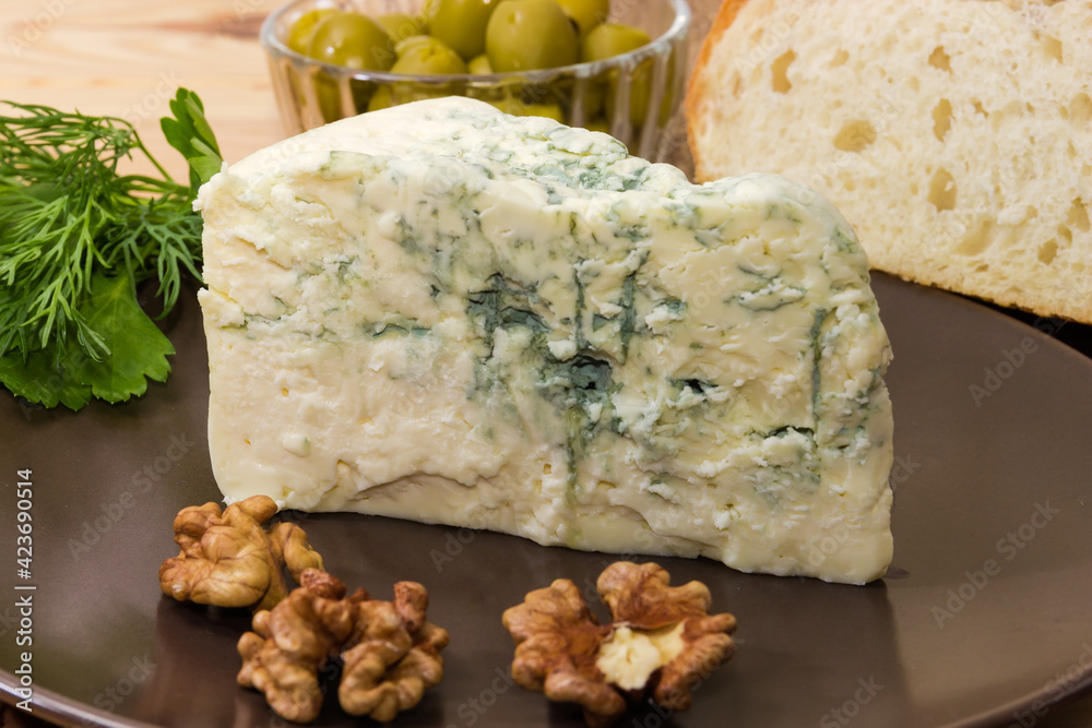 Piece of blue cheese with blue-grey mold on dish Piece of blue cheese with blue-grey mold on dish