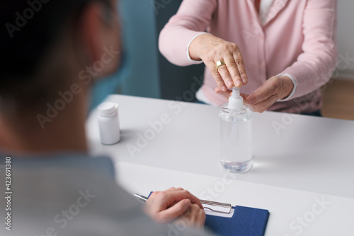 Senior woman sanitizing her hands in the doctor s office