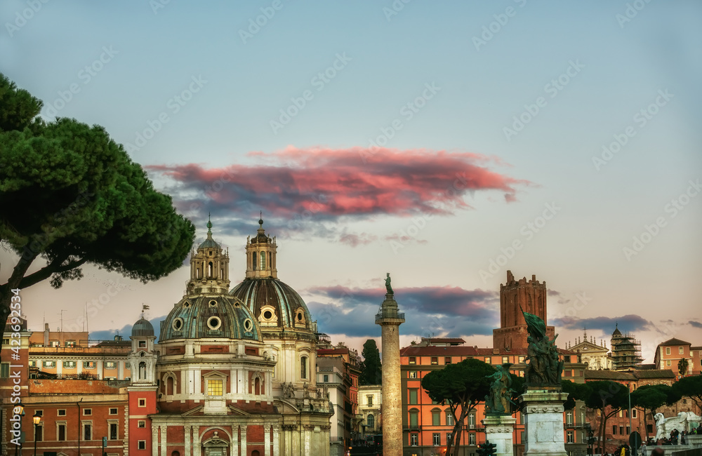 Streets of Rome with ancient buildings and domes of cathedrals in the sunset light.