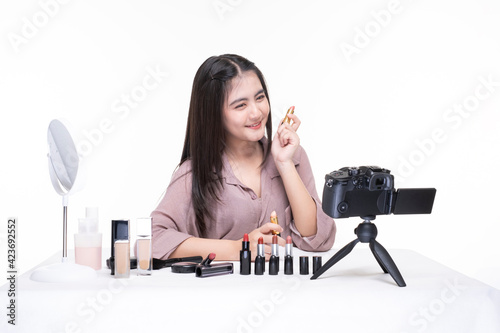 Young beautiful female professional beauty vlogger or blogger recording makeup tutorial online teaching. Young attractive girl makes makeup and recording video tutorial on the camera. 