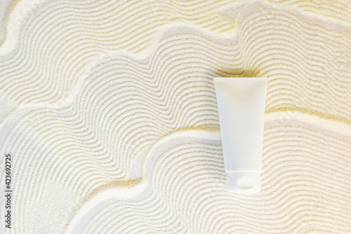 white cosmetic tube on a sand textured background. Copy space photo