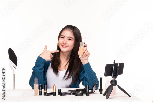Young female makeup artist doing video blog about cosmetics. Beauty female beauty vlogger bloggers doing a cosmetic makeup tutorial review of cosmetic products. Pretty woman doing makeup at home. 