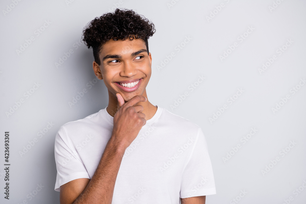 Portrait of brunet optimistic curly guy hand chin look empty space wear white t-shirt isolated on grey color background Portrait of brunet optimistic curly guy hand chin look empty space wear white t-shirt isolated on grey color background