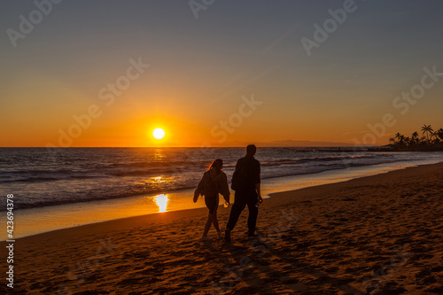 Man and woman by the ocean at sunset.