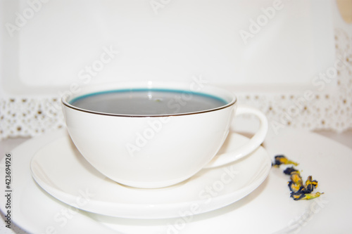 The mood color is blue - blue tea in a white mug  which stands on a white saucer and a white tray.