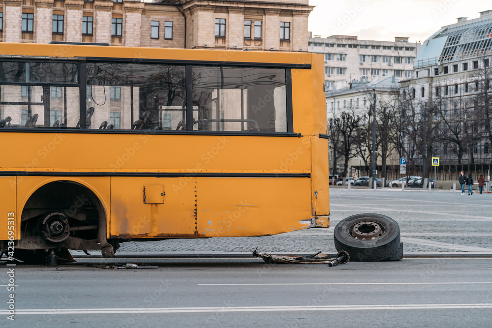 Fototapeta premium City bus with broken wheel stands on urban road.