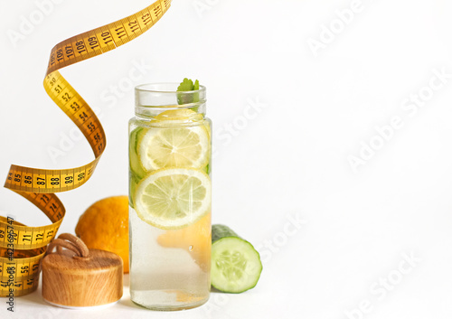 A bottle of lemon and cucumber detox and a centimeter tape.