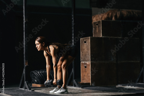 young woman at a crossfit style on dark gray background.