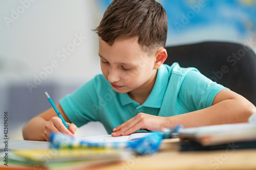 Wallpaper Mural little boy is sitting at his desk, doing his homework at home. child smiles happily and gains knowledge during quarantine period. digital concept e-learning, during epidemic, self-isolation. Torontodigital.ca