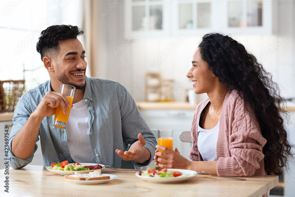 Cheerful Arab Couple Chatting And Laughing While Having Breakfast In Kitchen Cheerful Arab Couple Chatting And Laughing While Having Breakfast In Kitchen