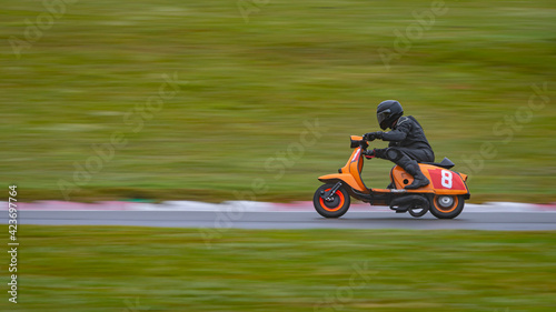 A panning shot of a racing scooter as it circuits a track.