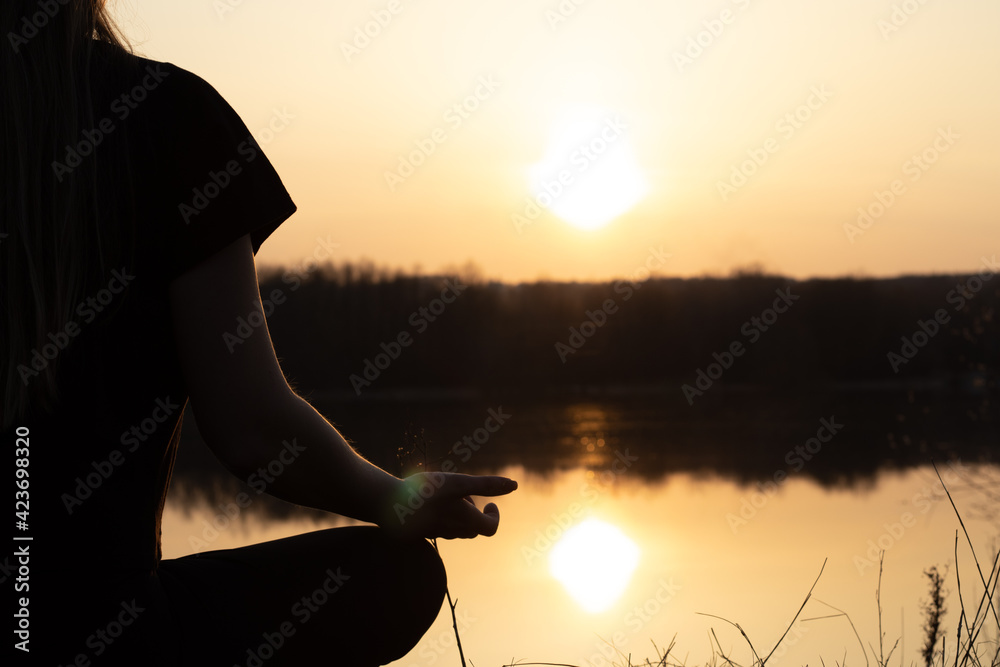 Woman relaxing on the river during sunset. Healthy lifestyle and yoga concept