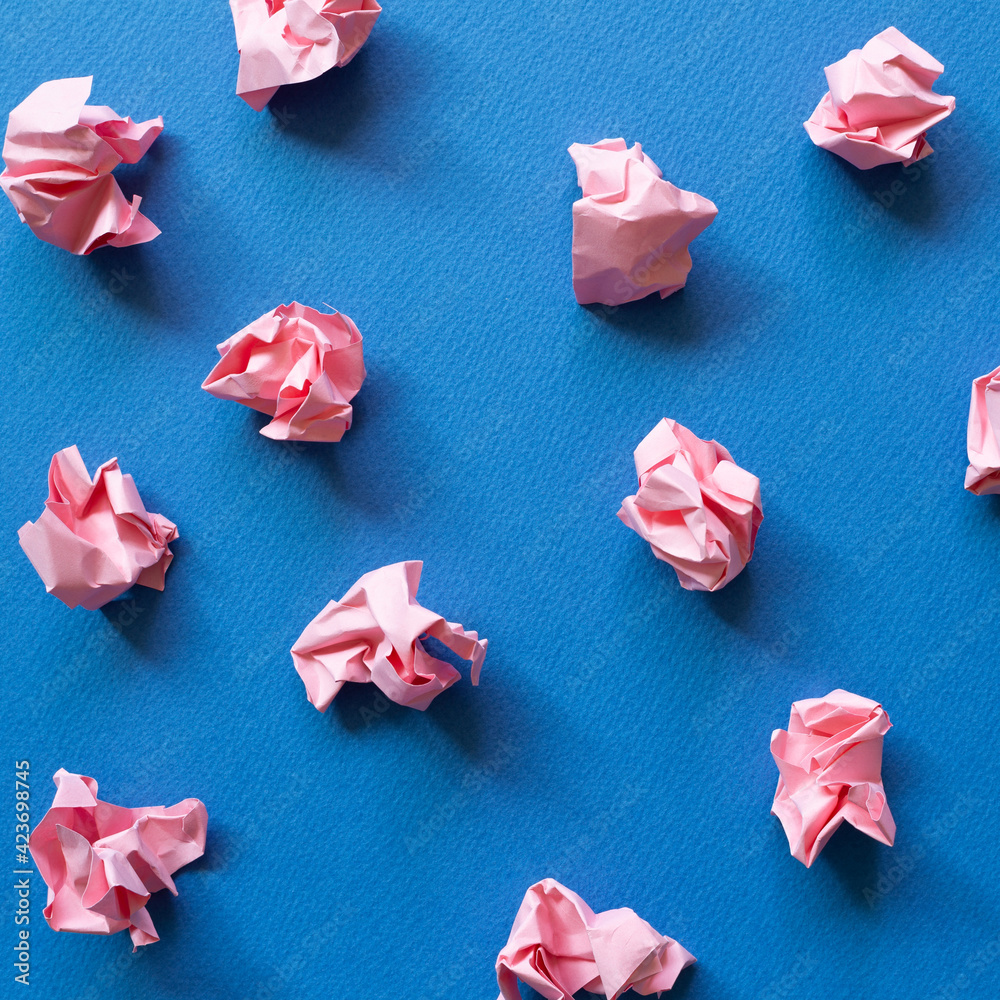 Pink crumpled paper balls on blue background. Creative idea concept