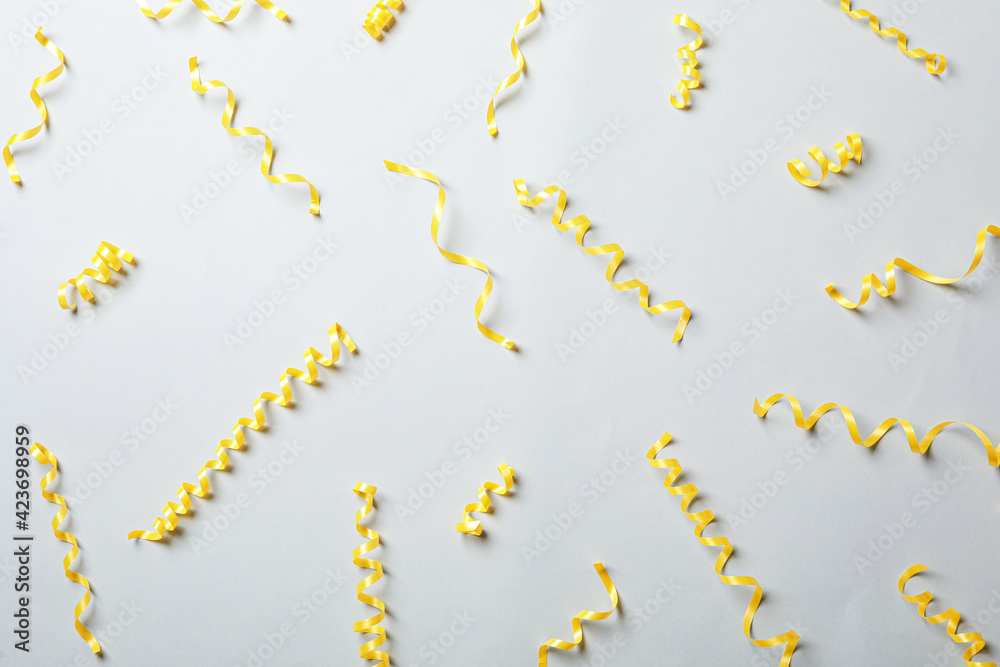 Yellow serpentine streamers on light background, flat lay