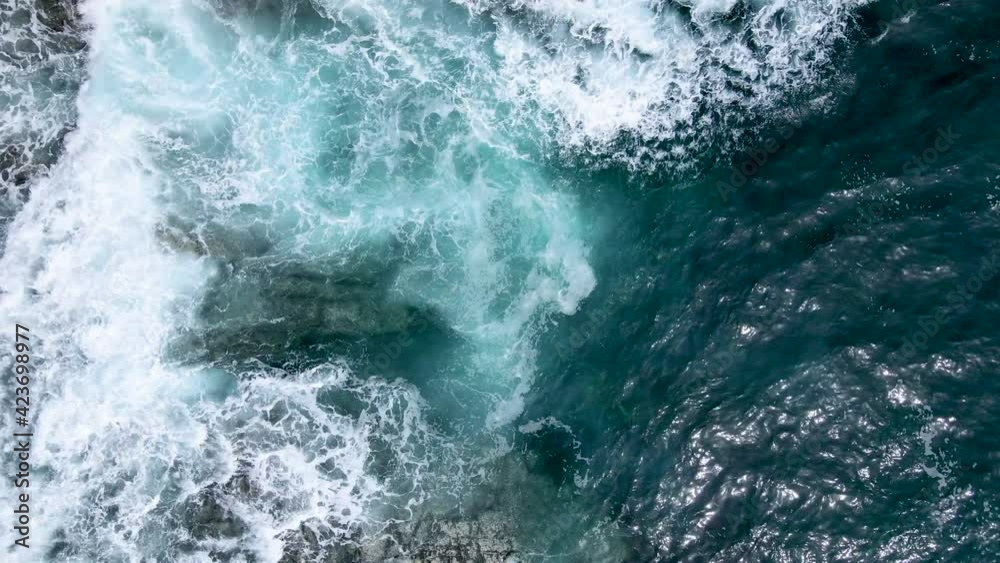 Impressive aerial video of powerful waves crashing at rocky cliffs and splashing white foam. Scenic top aerial view of teal ocean. Cinematic 4K drone nature video. Outdoor adventure and background.
