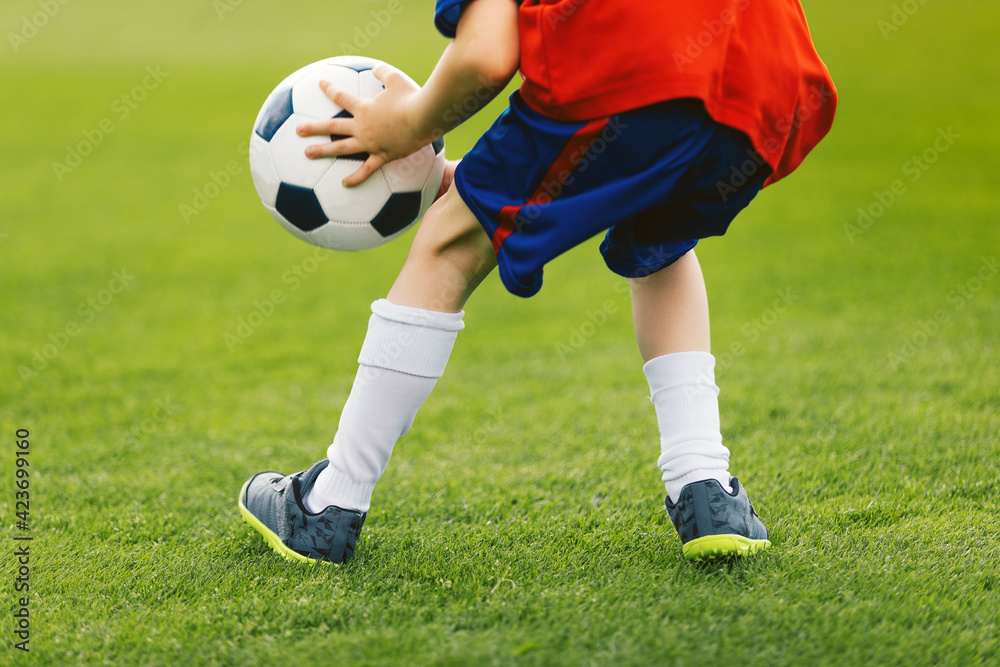Child Playing with Soccer Ball on Grass Field. Happy Kid Holding Classic Football Ball