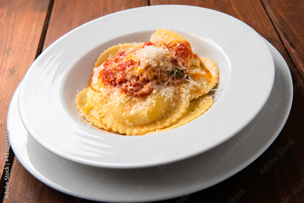 Piatto di ravioli di zafferano ripieni di ricotta con salsa di pomodoro e parmigiano, Cucina Italiana Piatto di ravioli di zafferano ripieni di ricotta con salsa di pomodoro e parmigiano, Cucina Italiana