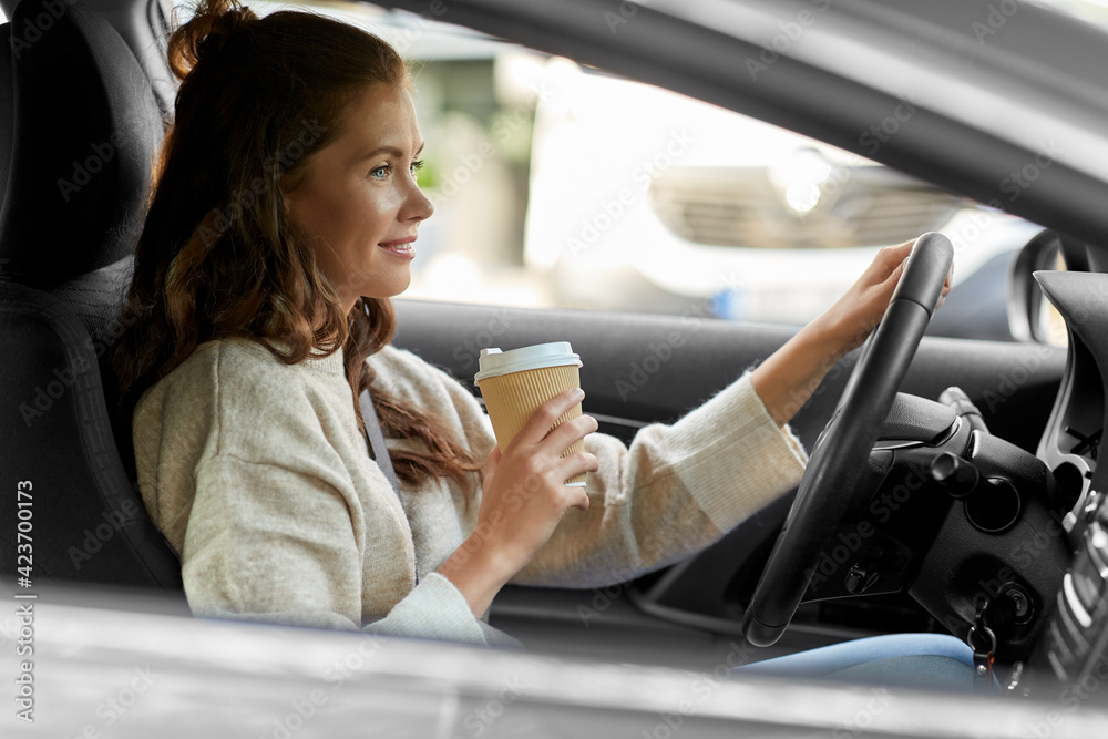 lifestyle and people concept - happy smiling young woman or female driver driving car and drinking takeaway coffee