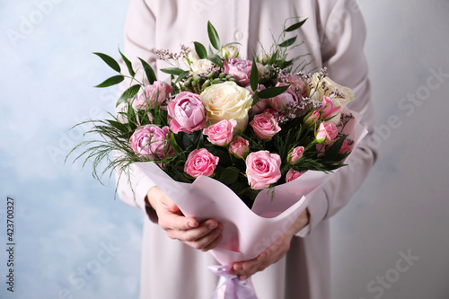 Fototapeta Naklejka Na Ścianę i Meble -  Woman with bouquet of beautiful roses on light blue background, closeup