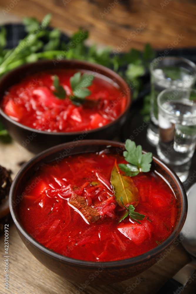 Stylish brown clay bowls with Ukrainian borsch served on wooden table Stylish brown clay bowls with Ukrainian borsch served on wooden table