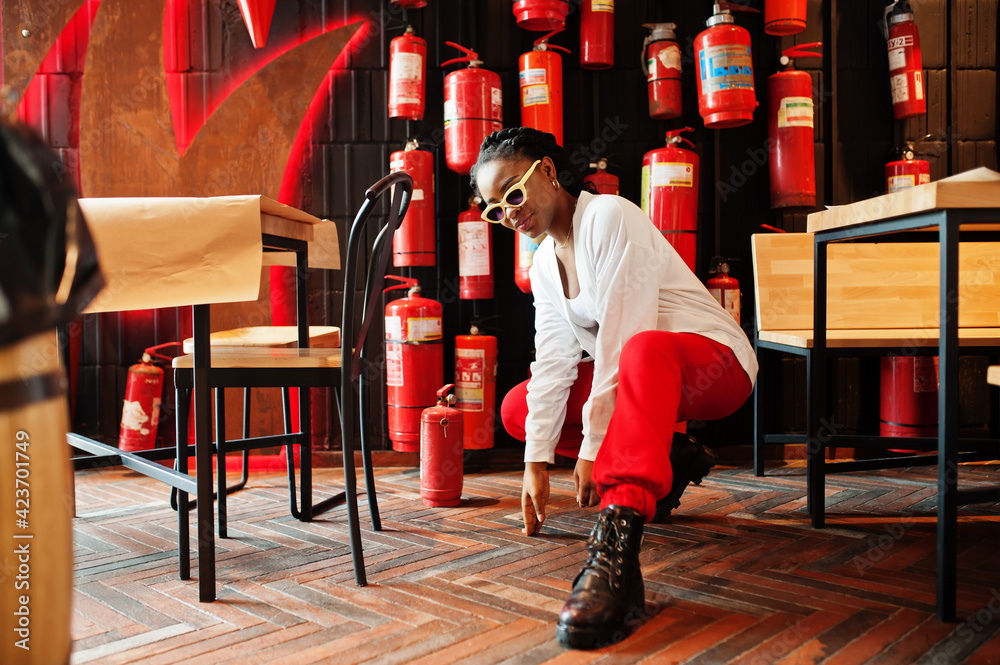 African woman posed against wall with old extinguisher.