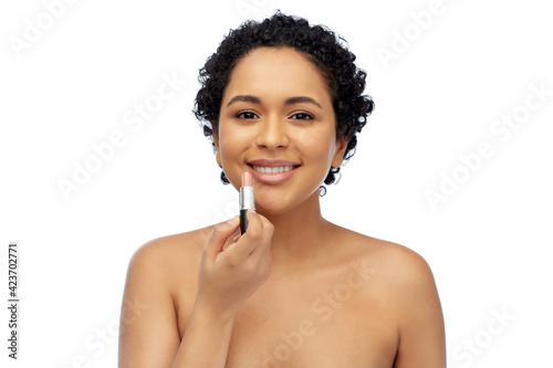 beauty, make up and cosmetics concept - beautiful young african american woman applying lipstick over white background