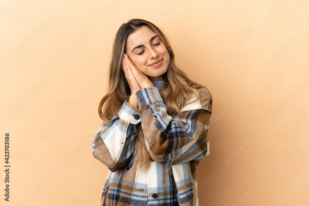 Young caucasian woman isolated on beige background making sleep gesture in dorable expression Young caucasian woman isolated on beige background making sleep gesture in dorable expression
