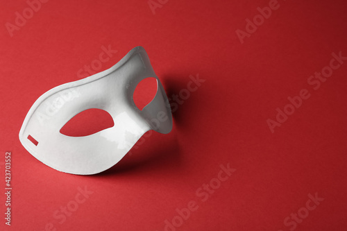 White theatre mask on red background, space for text
