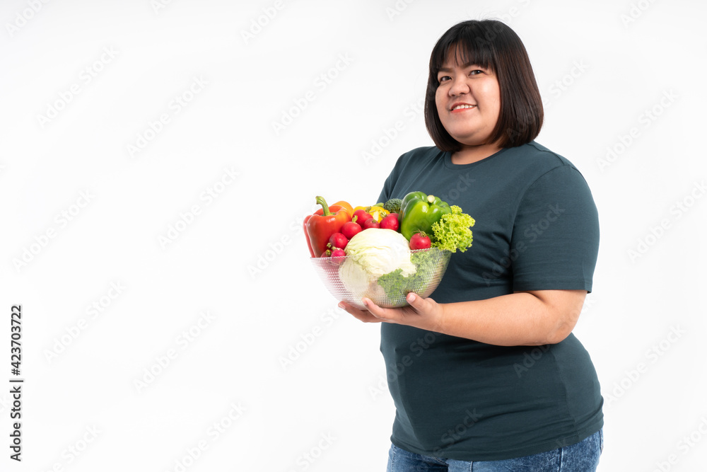 Happy Asian overweight woman holding a vegetable basket and smiling on isolated white background, Concept of good health comes from eating a nutritious diet. Happy Asian overweight woman holding a vegetable basket and smiling on isolated white background, Concept of good health comes from eating a nutritious diet.