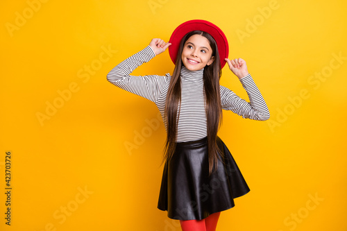 Portrait of attractive cheerful long-haired girl touching hat thinking creating idea isolated over bright yellow color background