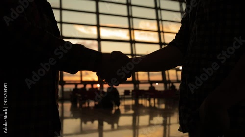 silhouette of two business people handshake in airport sunset light. Two man meet after arrival in airport.