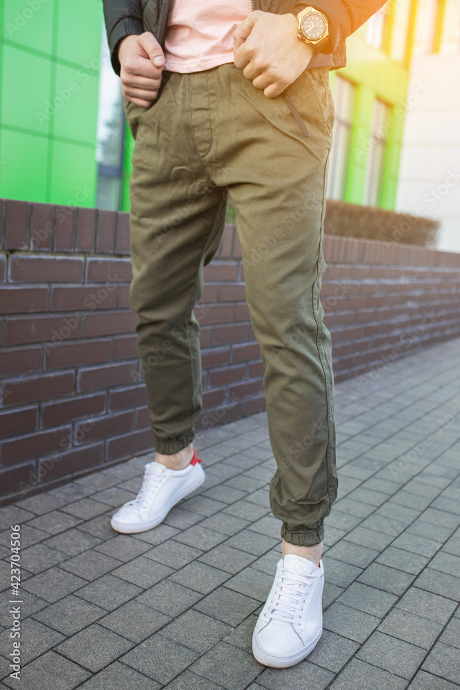 Young fashion man's legs with white sneakers. White shoes Young fashion man's legs with white sneakers. White shoes