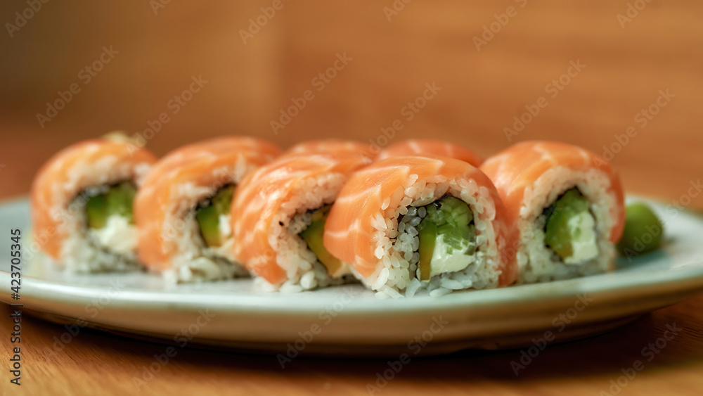 Closeup of set of Philadelphia sushi rolls with salmon, avocado, cream cheese on white plate