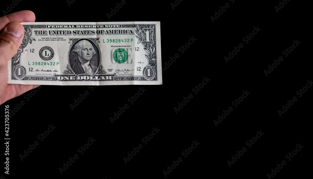Hand holding 1 dollar over black background space Hand holding 1 dollar over black background space