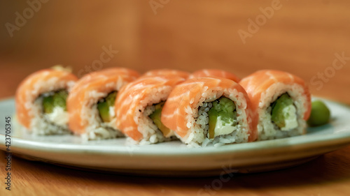 Closeup of set of Philadelphia sushi rolls with salmon, avocado, cream cheese on white plate