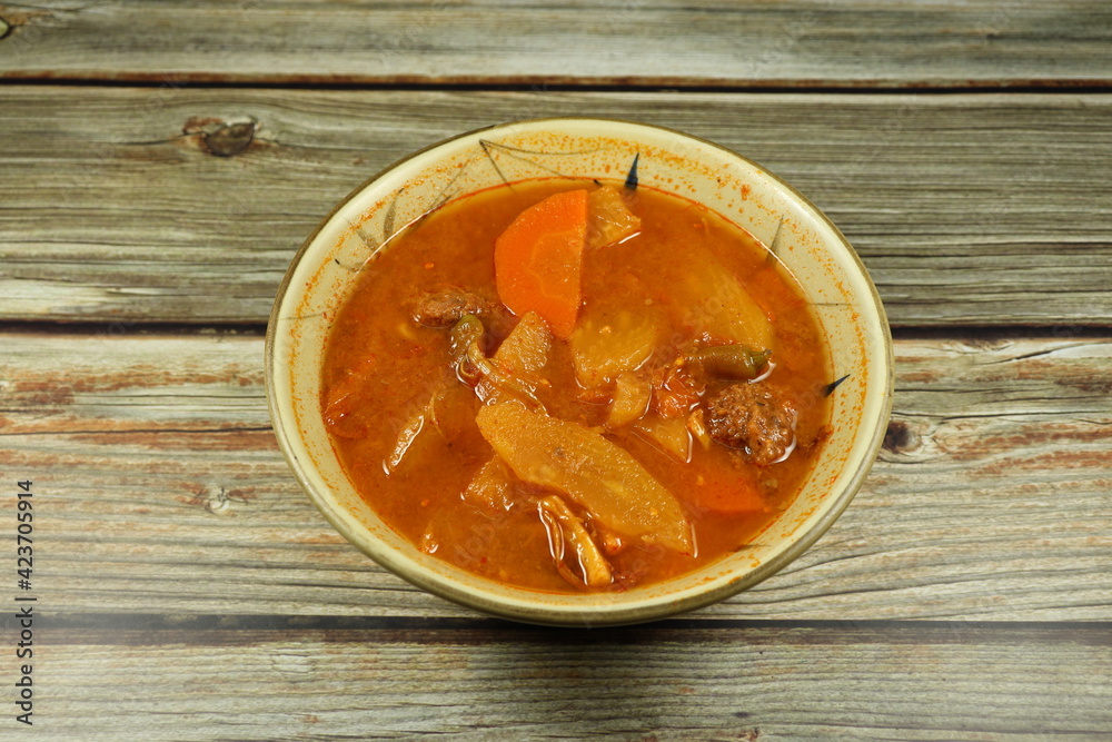 Traditional red curry soup of mixed fresh vegetable serving in the bowl. Famous spicy and sour soup menu in Asian restaurant. Traditional red curry soup of mixed fresh vegetable serving in the bowl. Famous spicy and sour soup menu in Asian restaurant.