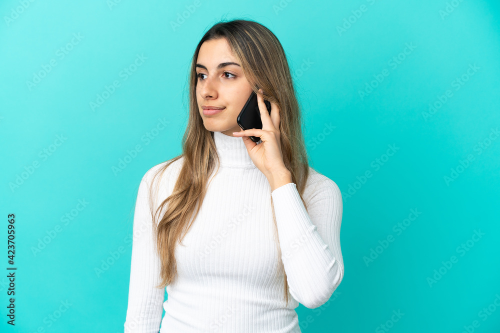 Young caucasian woman using mobile phone isolated on blue background looking to the side Young caucasian woman using mobile phone isolated on blue background looking to the side