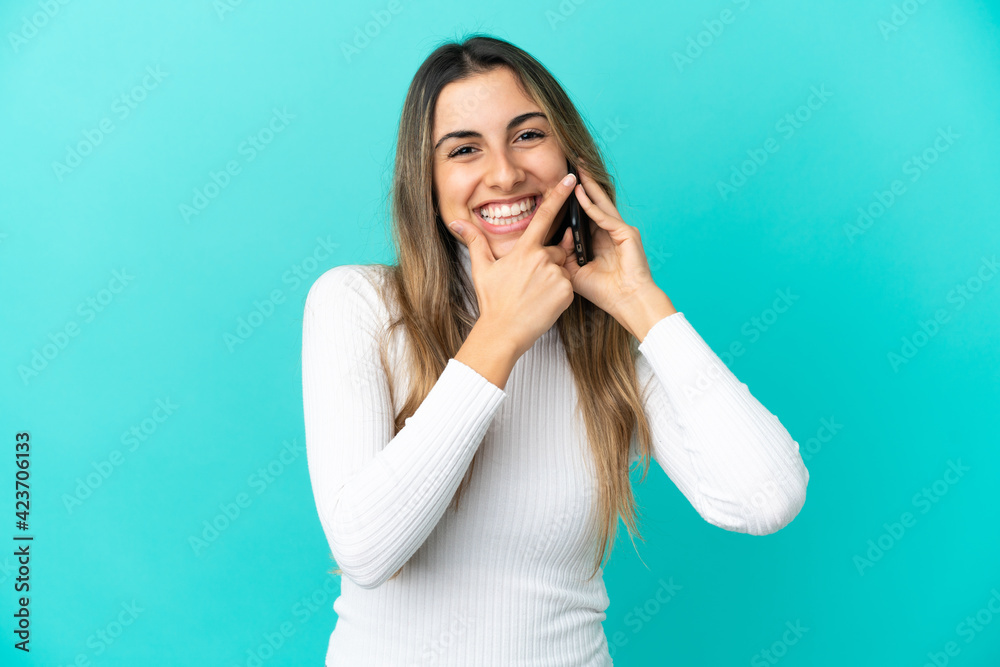 Fototapeta premium Young caucasian woman using mobile phone isolated on blue background happy and smiling