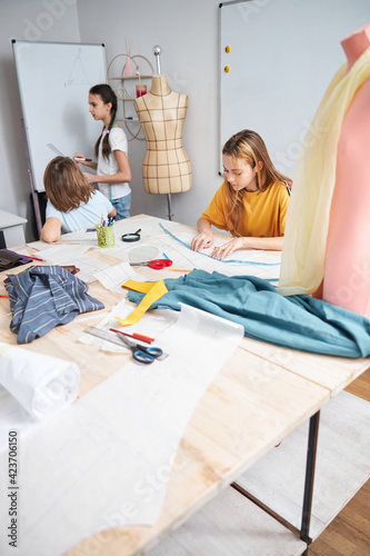 Cute female children working in sewing workshop