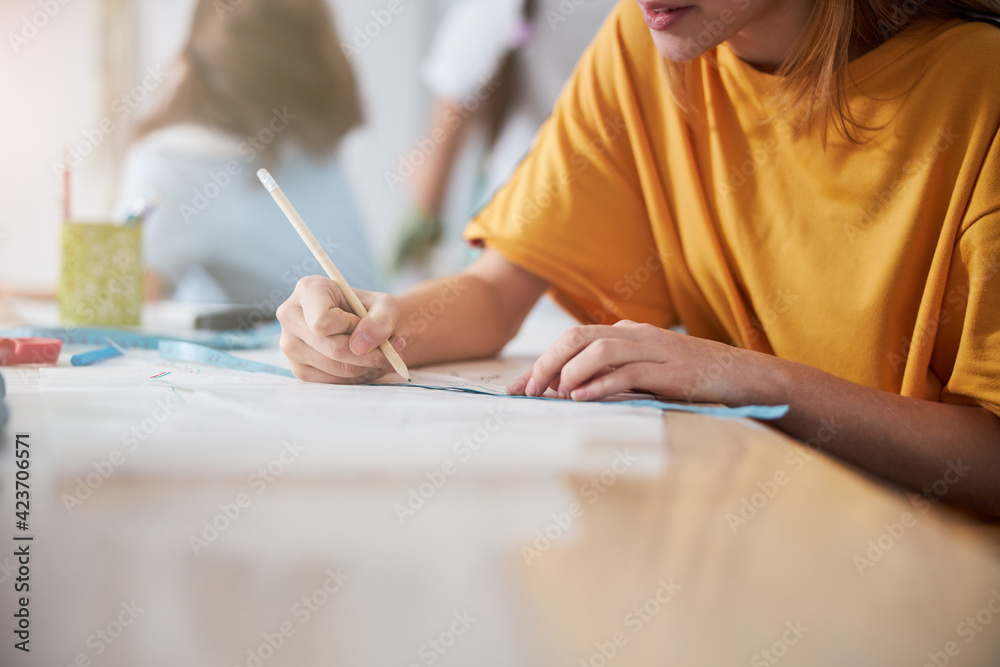 Female child drawing clothing pattern in sewing workshop Female child drawing clothing pattern in sewing workshop