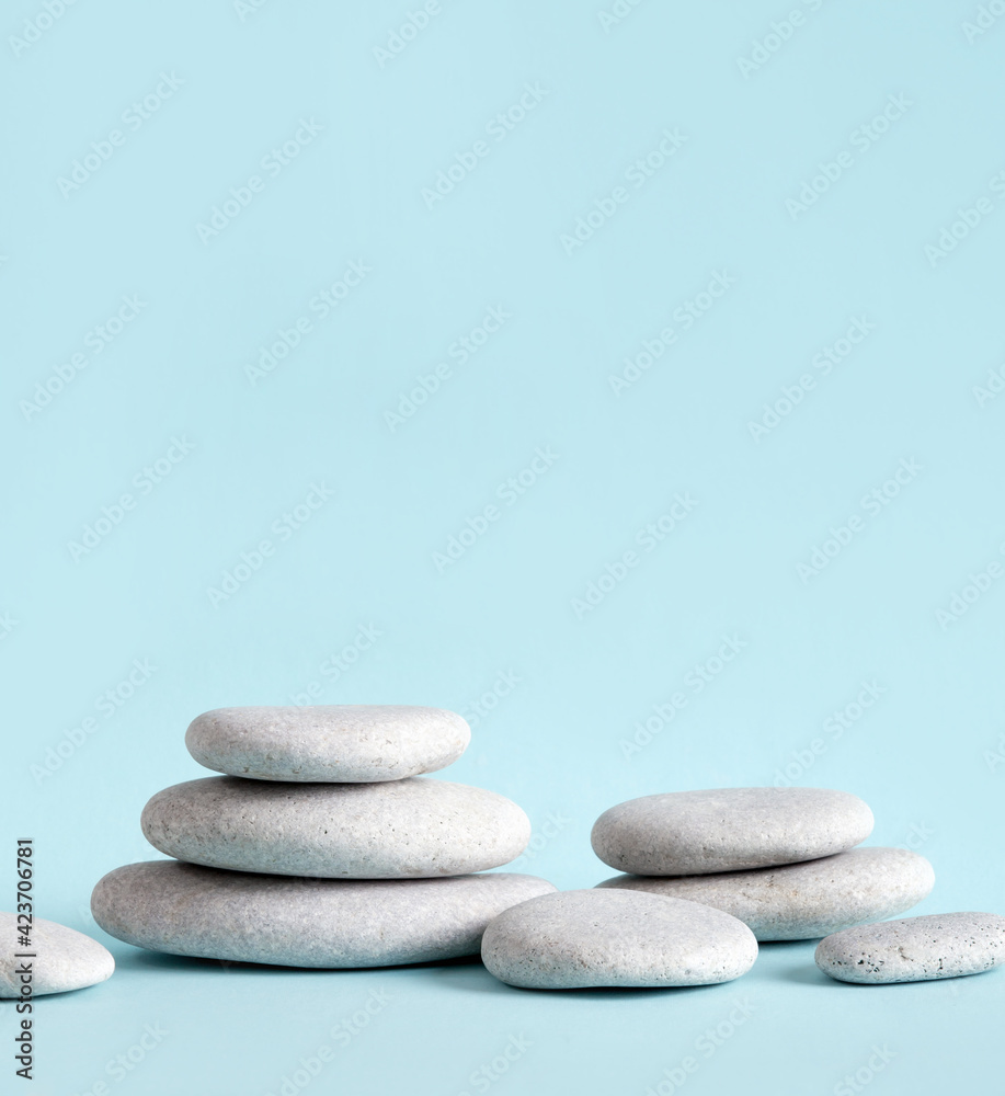 Minimalist beauty products background concept. Gray color flat sea stones stacked like an pedestal lot of copy space on blue background.