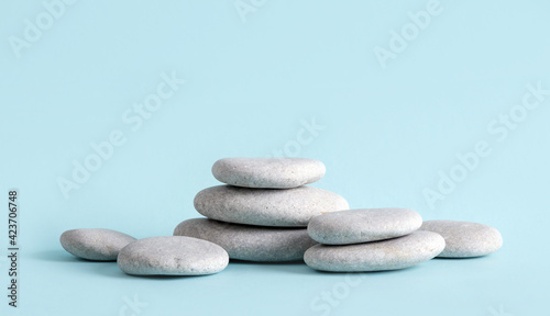 Minimalist beauty products background concept. Gray color flat sea stones stacked like an pedestal lot of copy space on blue background.